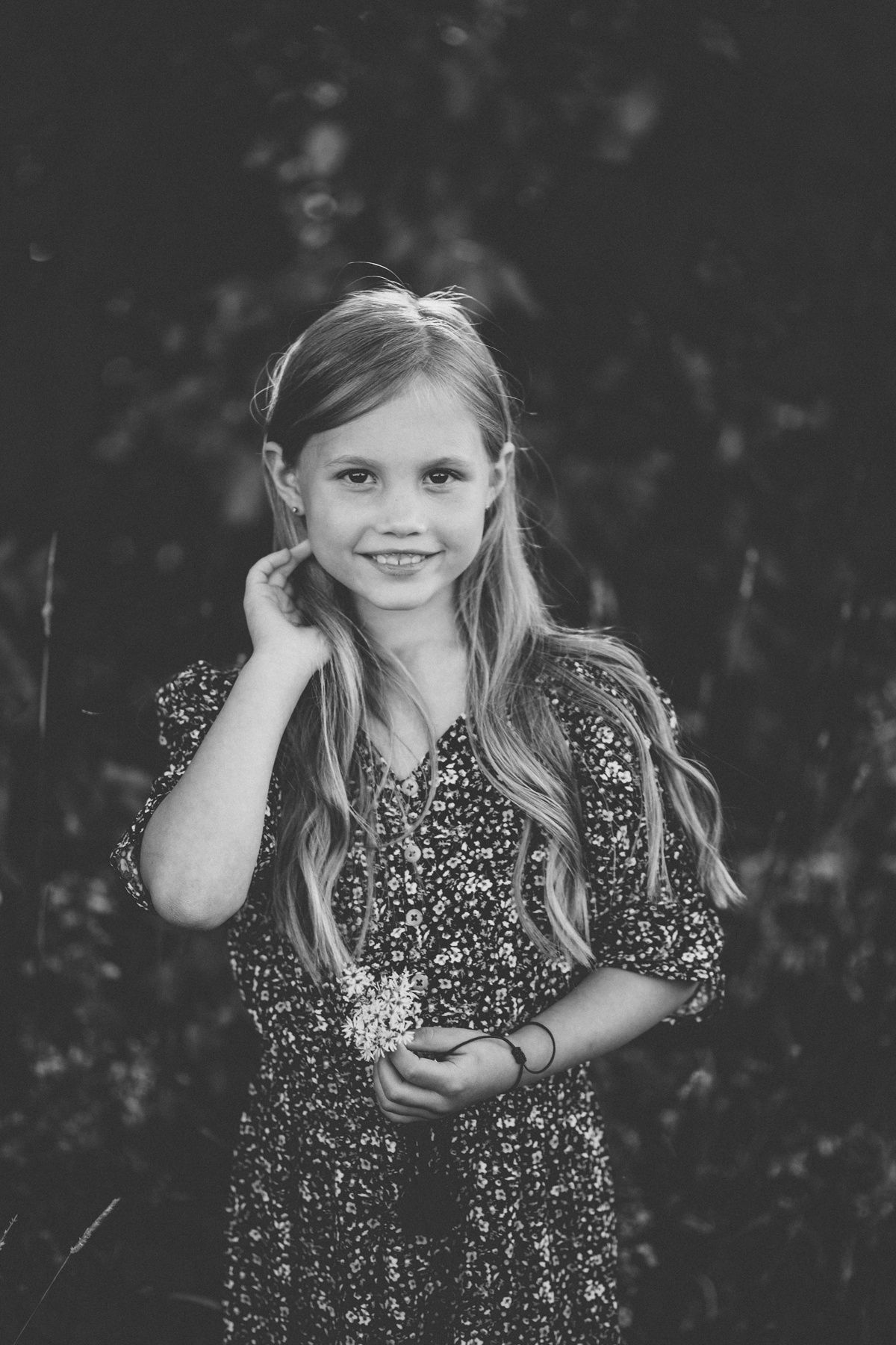 Black and white portrait of child in patterned dress outdoors.