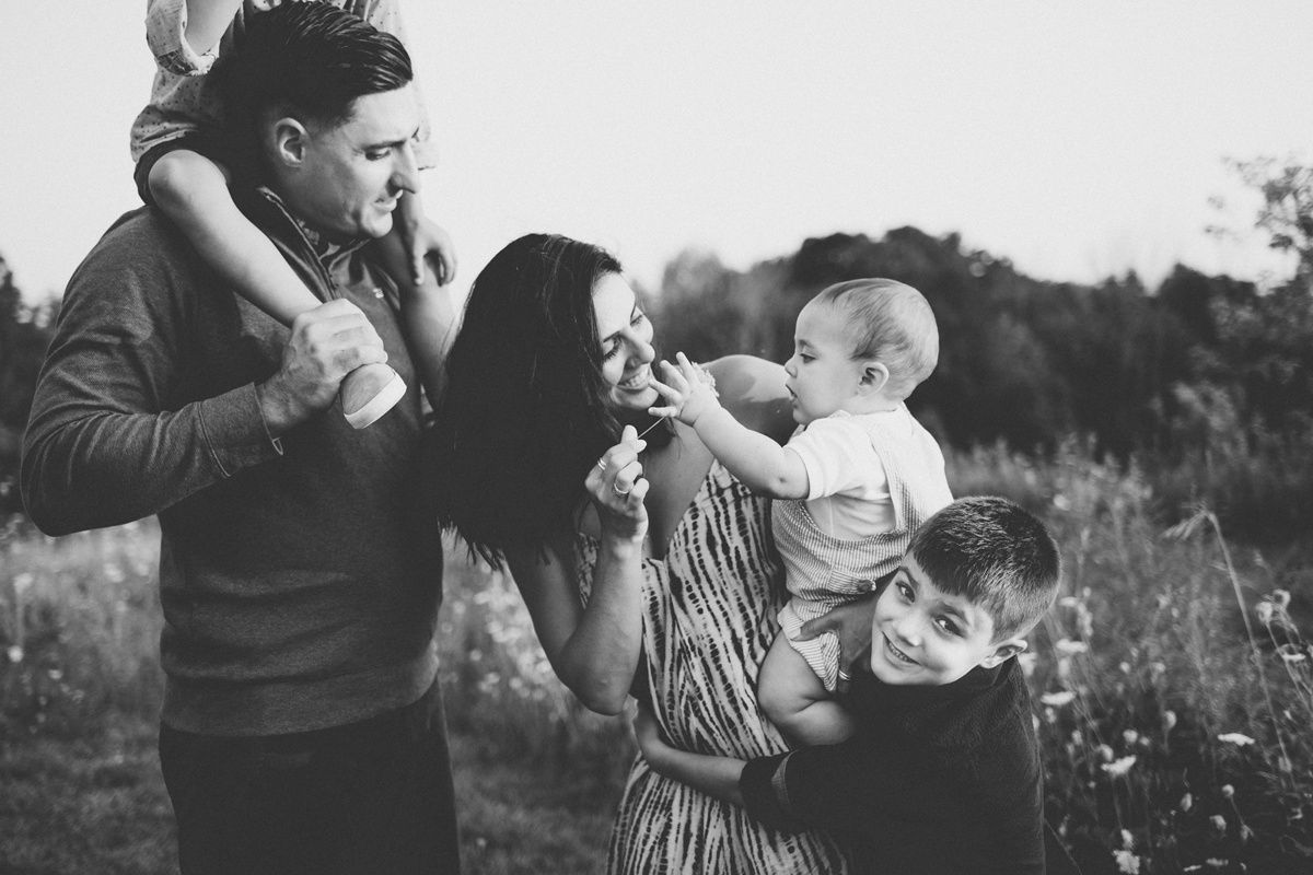 Family of four sharing joyful moments together in a wildflower field.