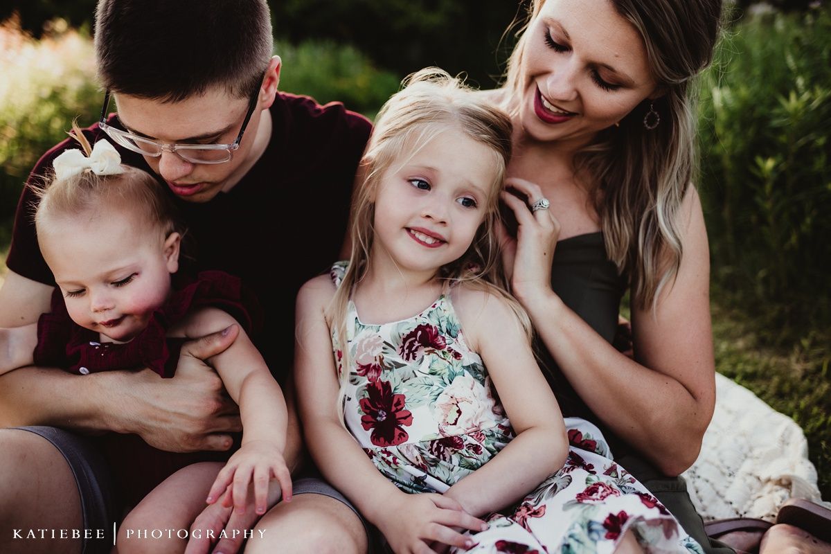 A playful family moment captured on a picnic blanket in golden evening light.