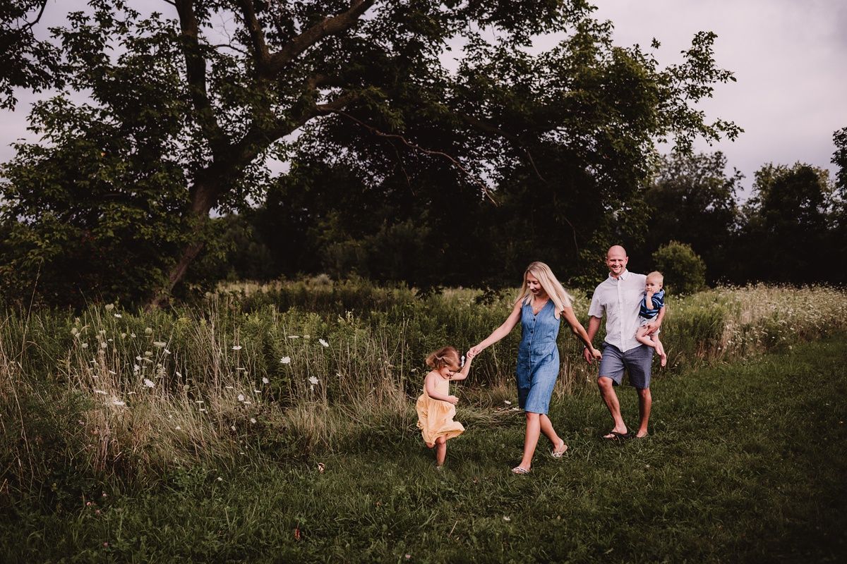 Family walking together through a scenic meadow path at sunset.