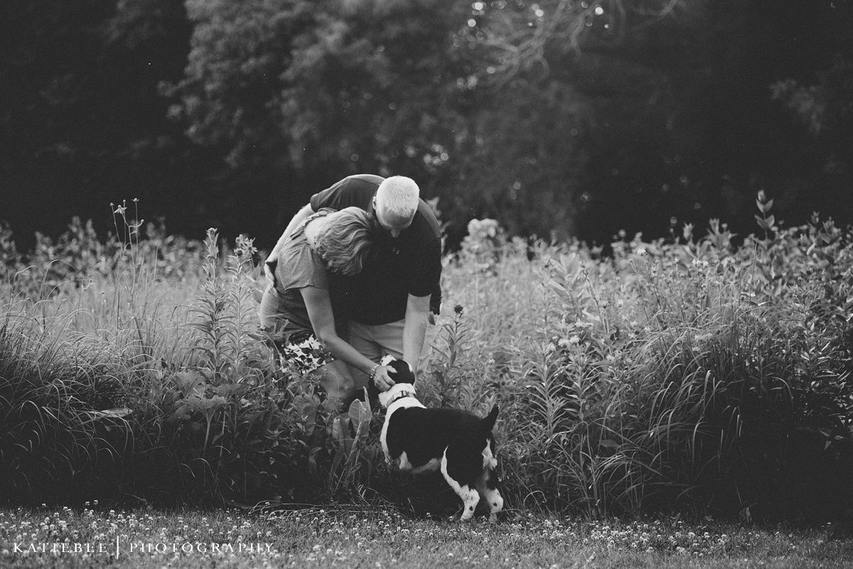 Black and white image of someone playing with a border collie in a meadow.