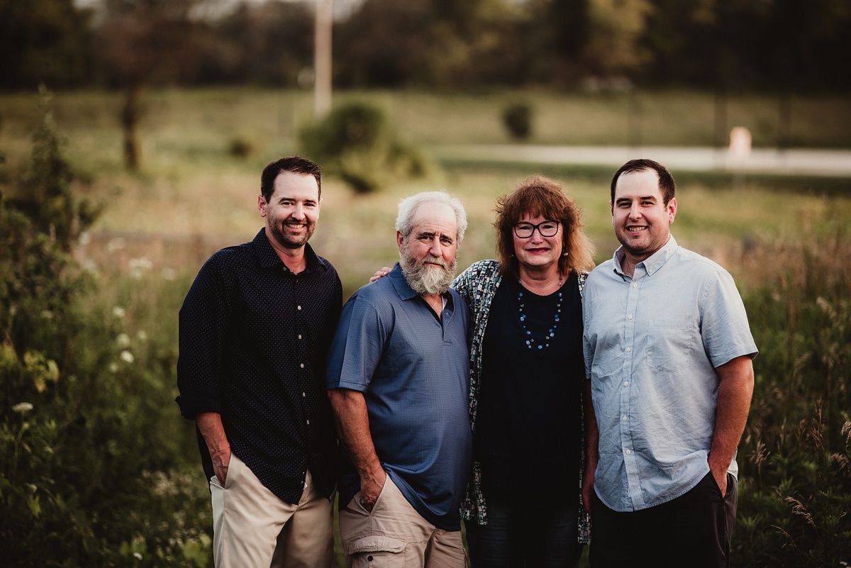 A group of four people poses together outdoors during golden hour.