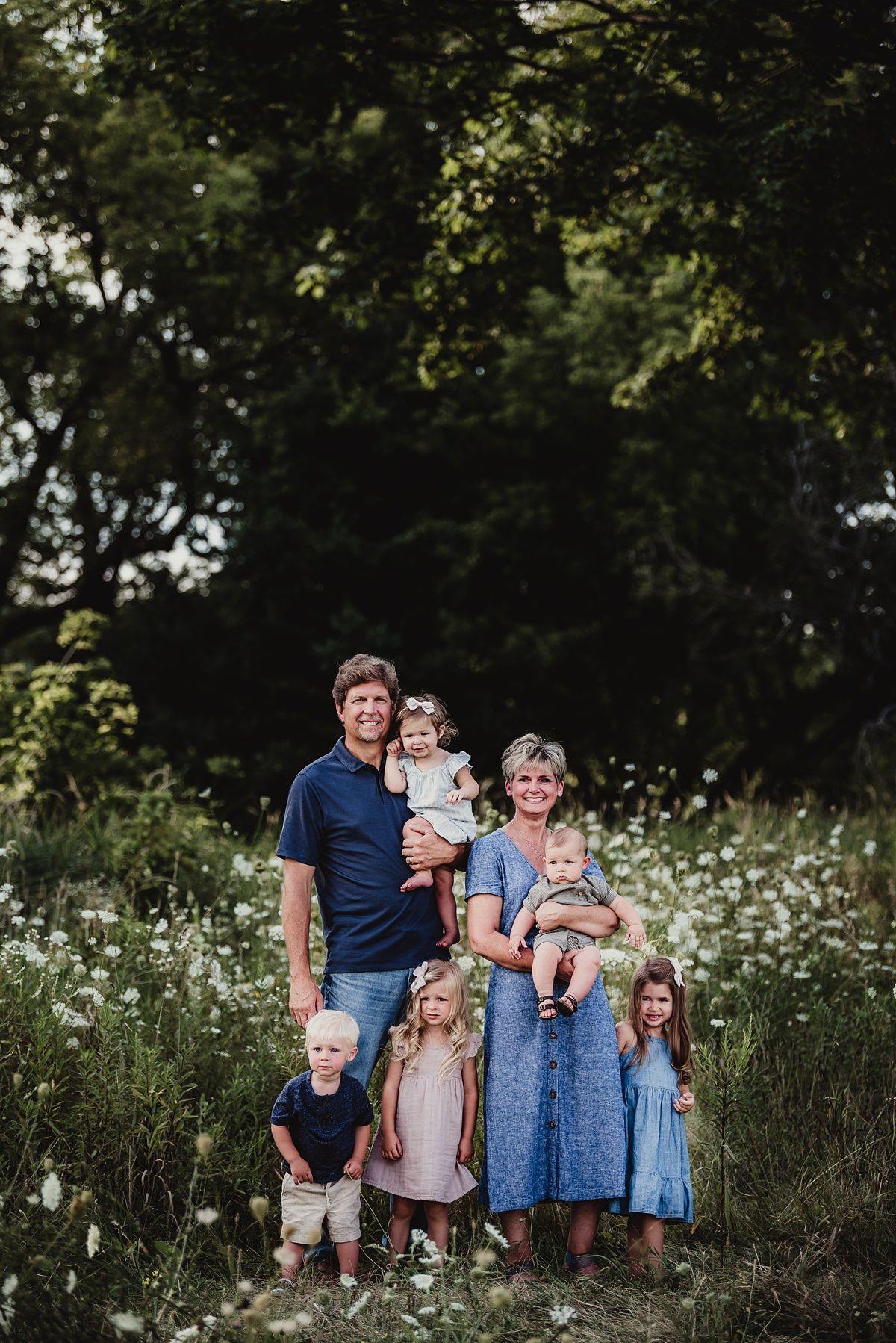 Family portrait in a blooming meadow surrounded by white wildflowers.
