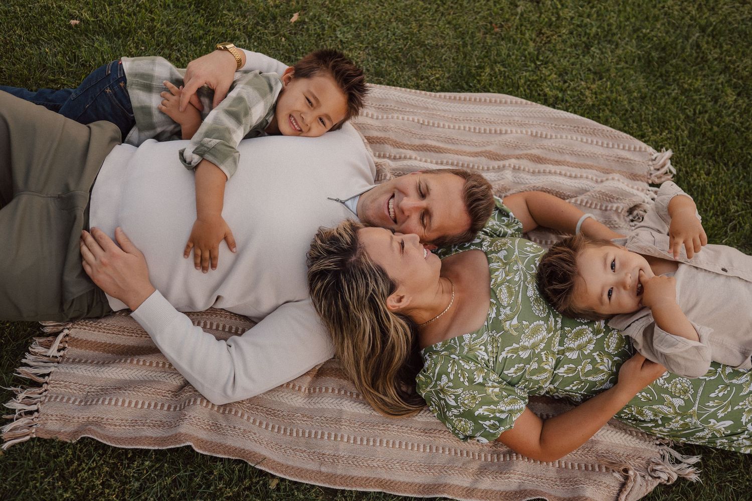 A tender family moment captured on a picnic blanket in the grass during a lifestyle photography session.