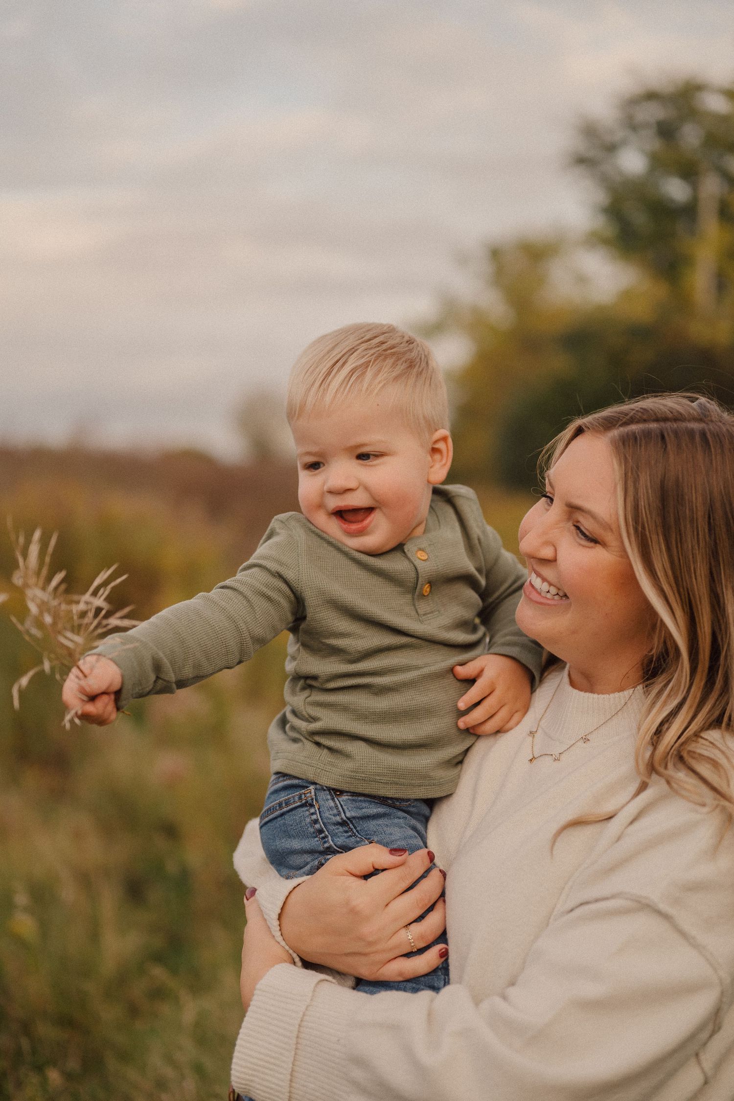 A joyful outdoor photo session in a natural field setting during golden hour with playful expressions and warm tones.