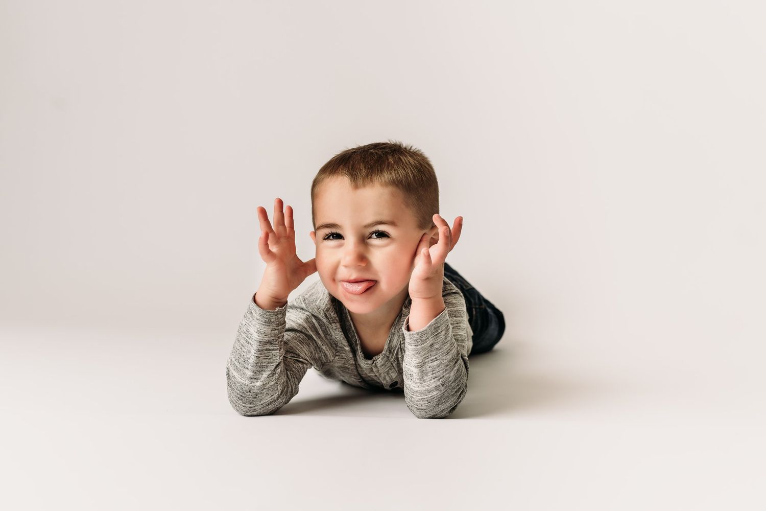 Fun pose with hands near ears while lying on white background.