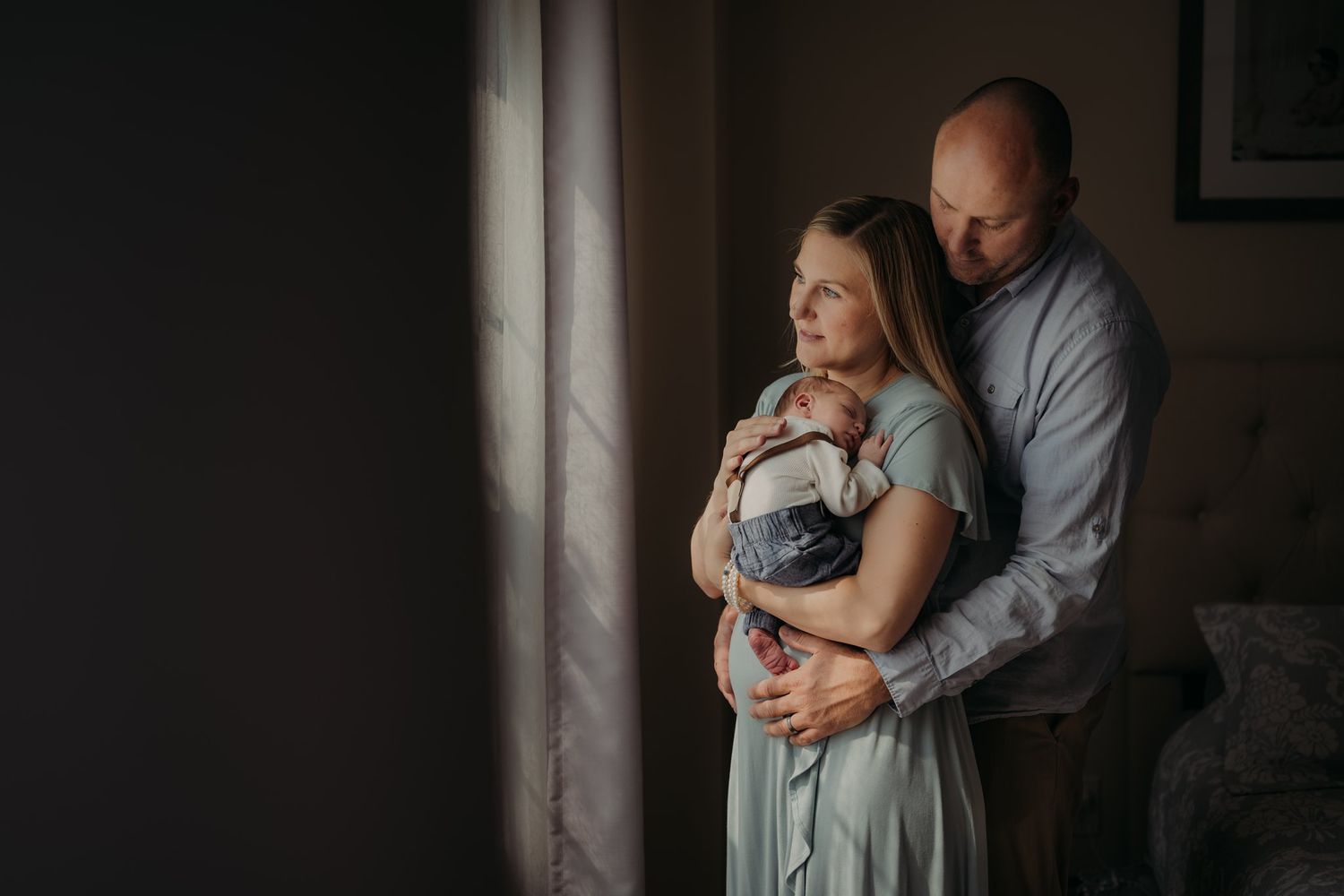 Moody family portrait with dramatic window lighting in neutral tones.