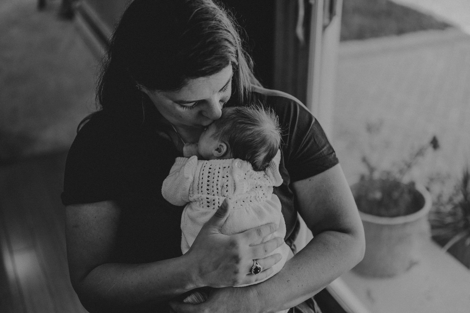 Black and white image of a parent tenderly holding their newborn close.