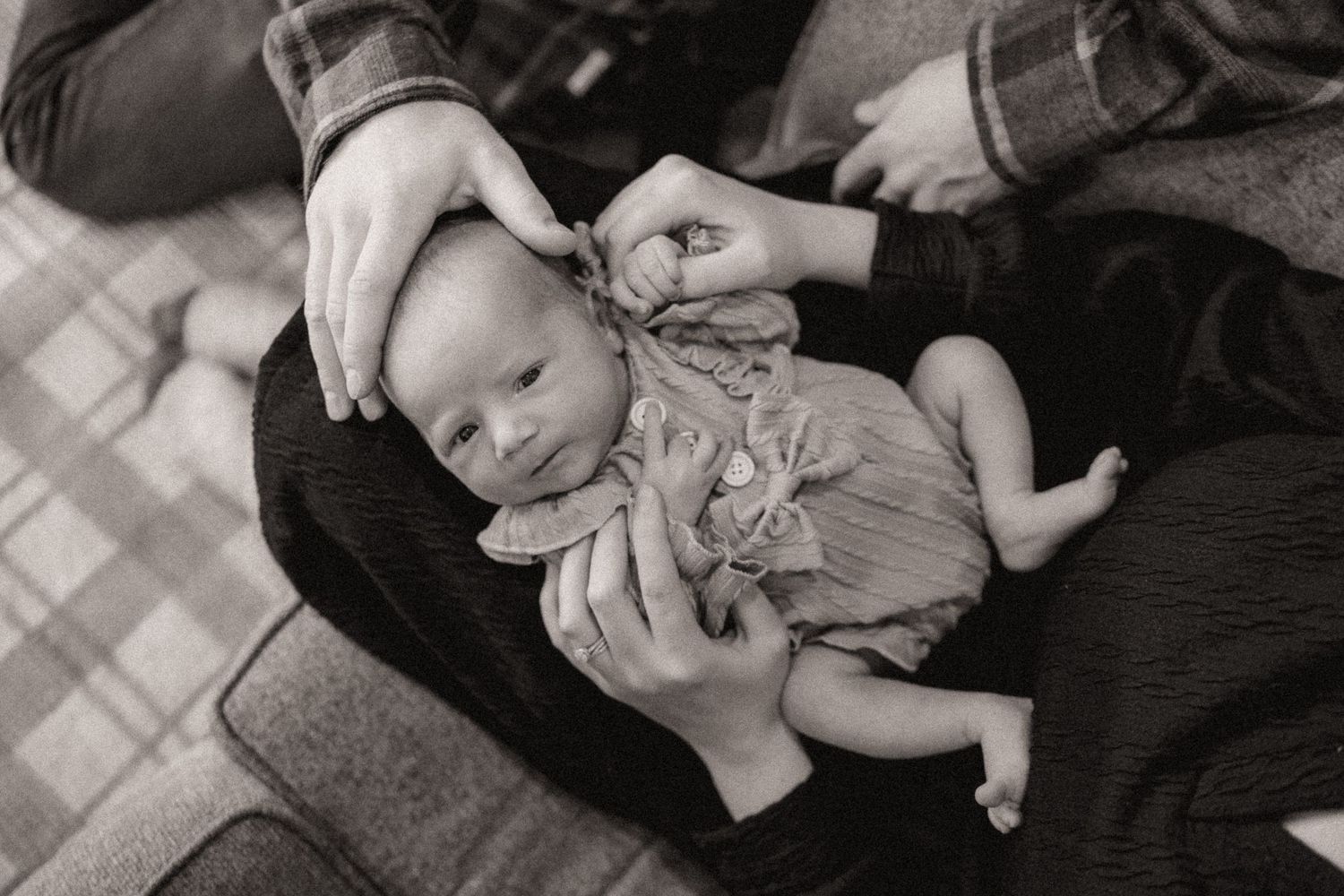 Intimate monochrome portrait of newborn baby being cradled during peaceful moment.