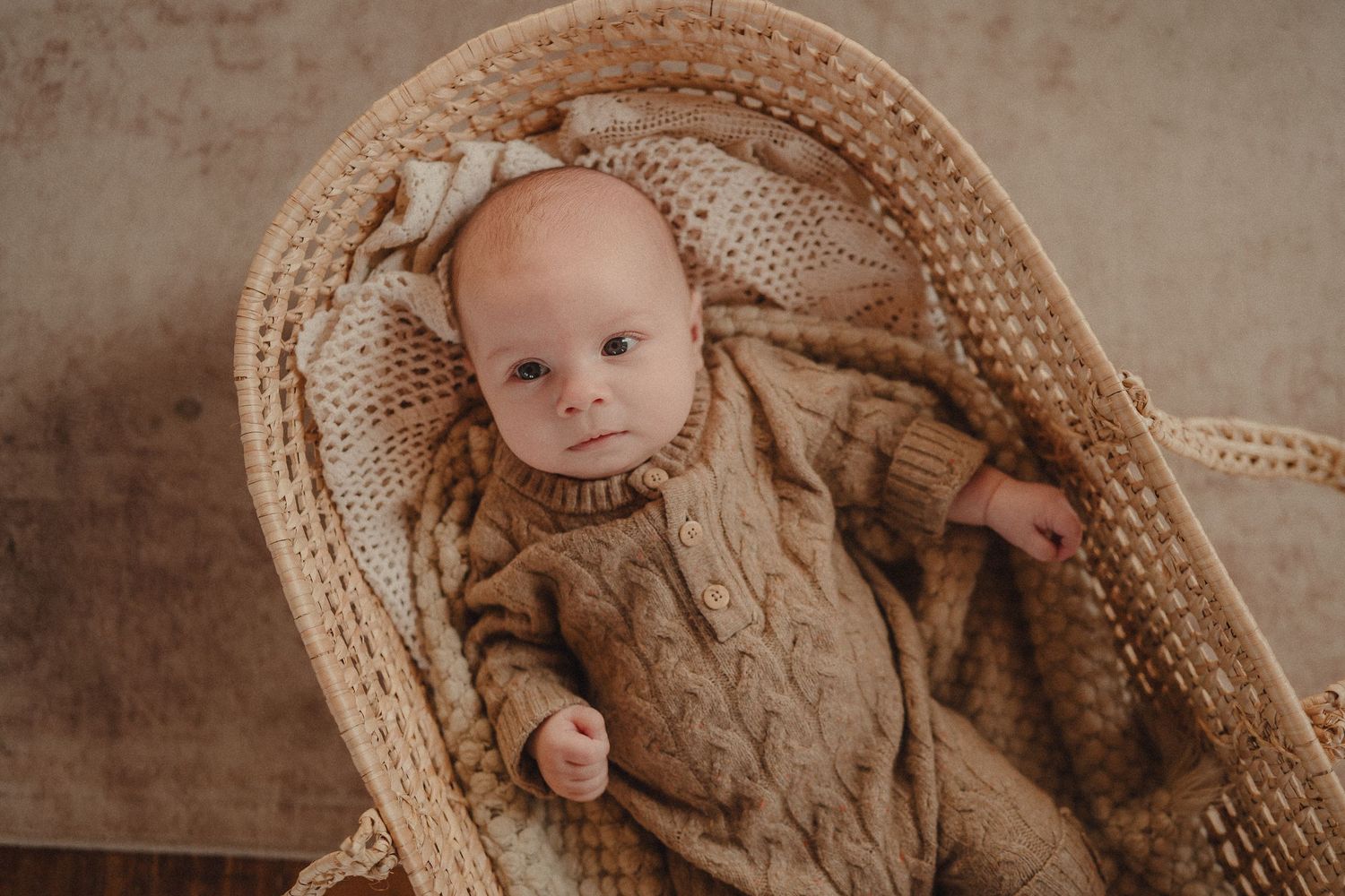 Newborn photography series featuring baby in cozy woven basket with brown teddy bear.