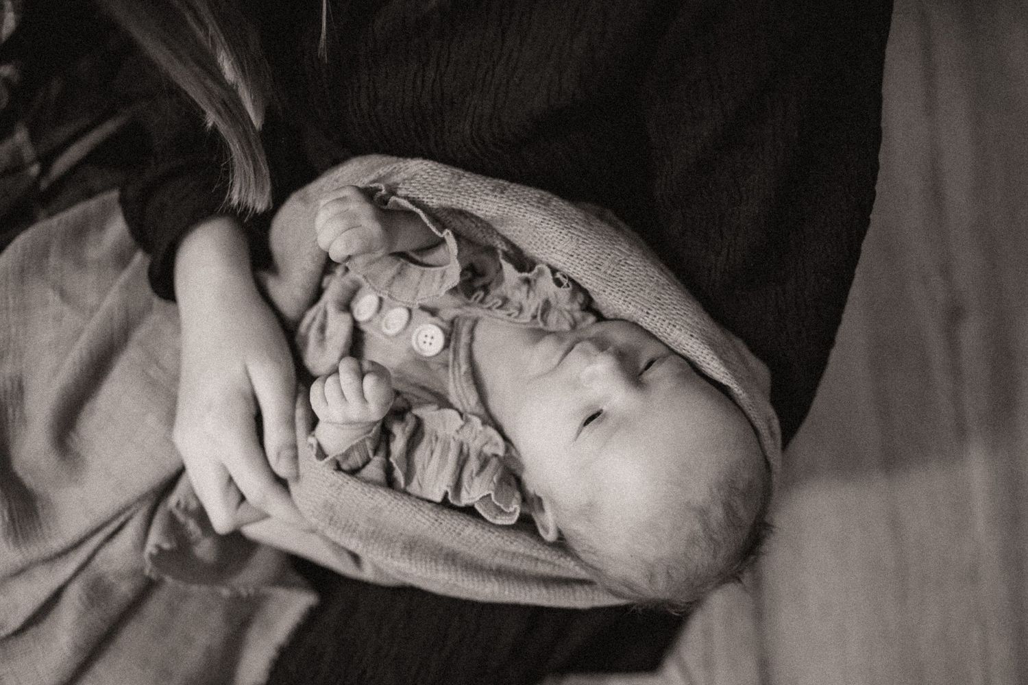 A series of black and white photographs showing a newborn baby in different sleeping poses on soft blankets.