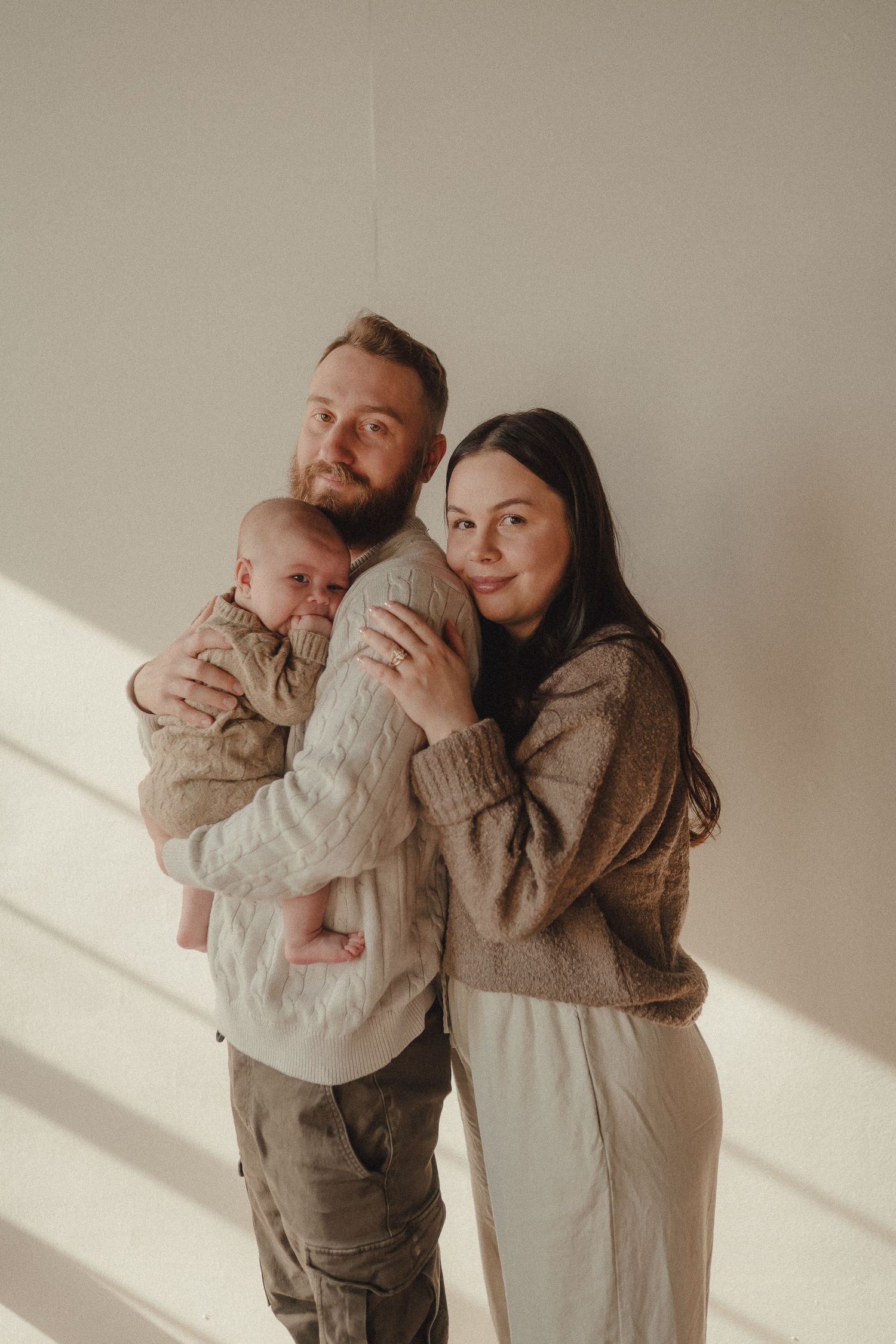 Candid family moments captured in soft natural light against neutral backdrop.