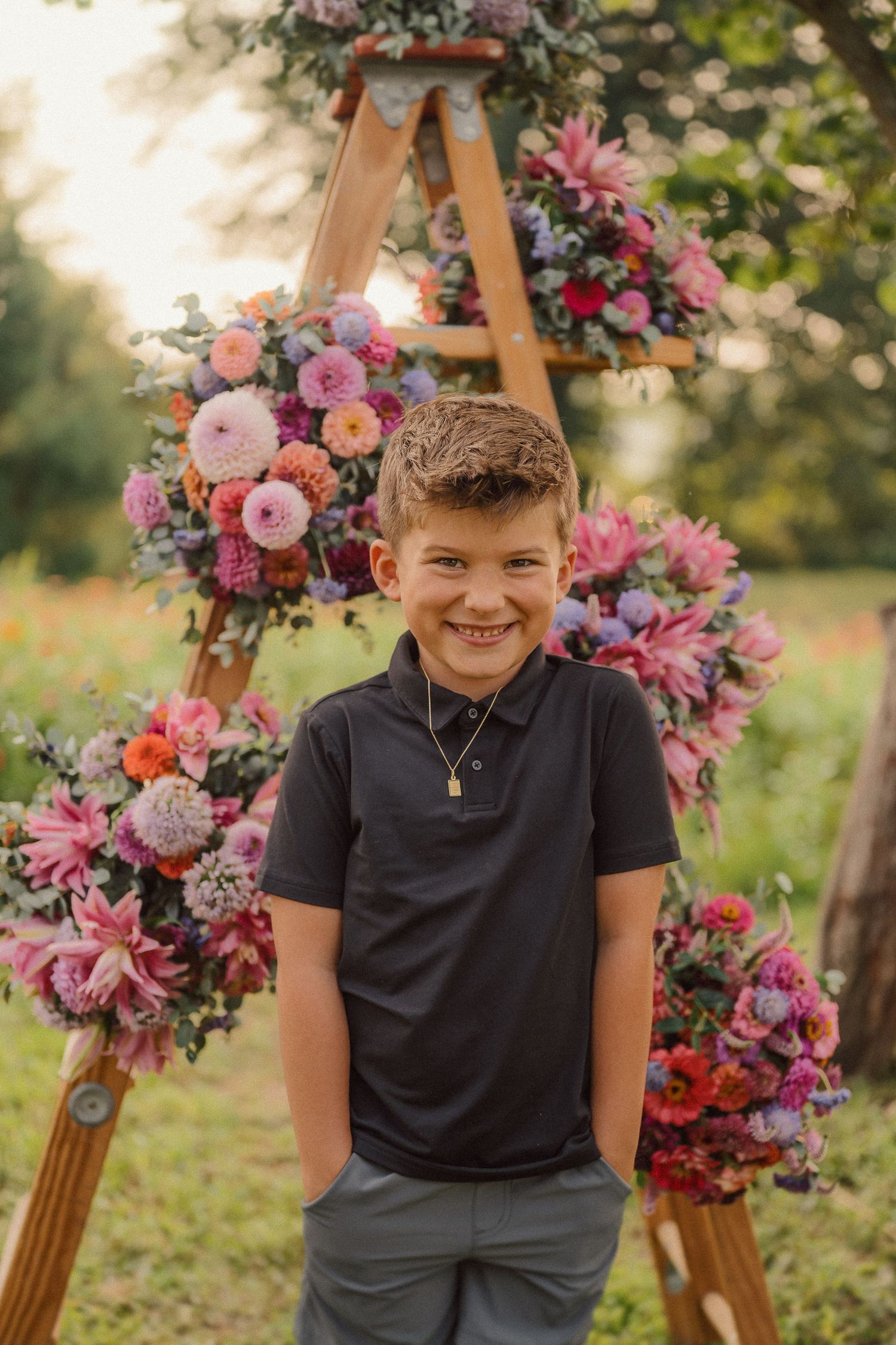 Joyful outdoor photo session with a wooden easel decorated with pink and purple blooms.