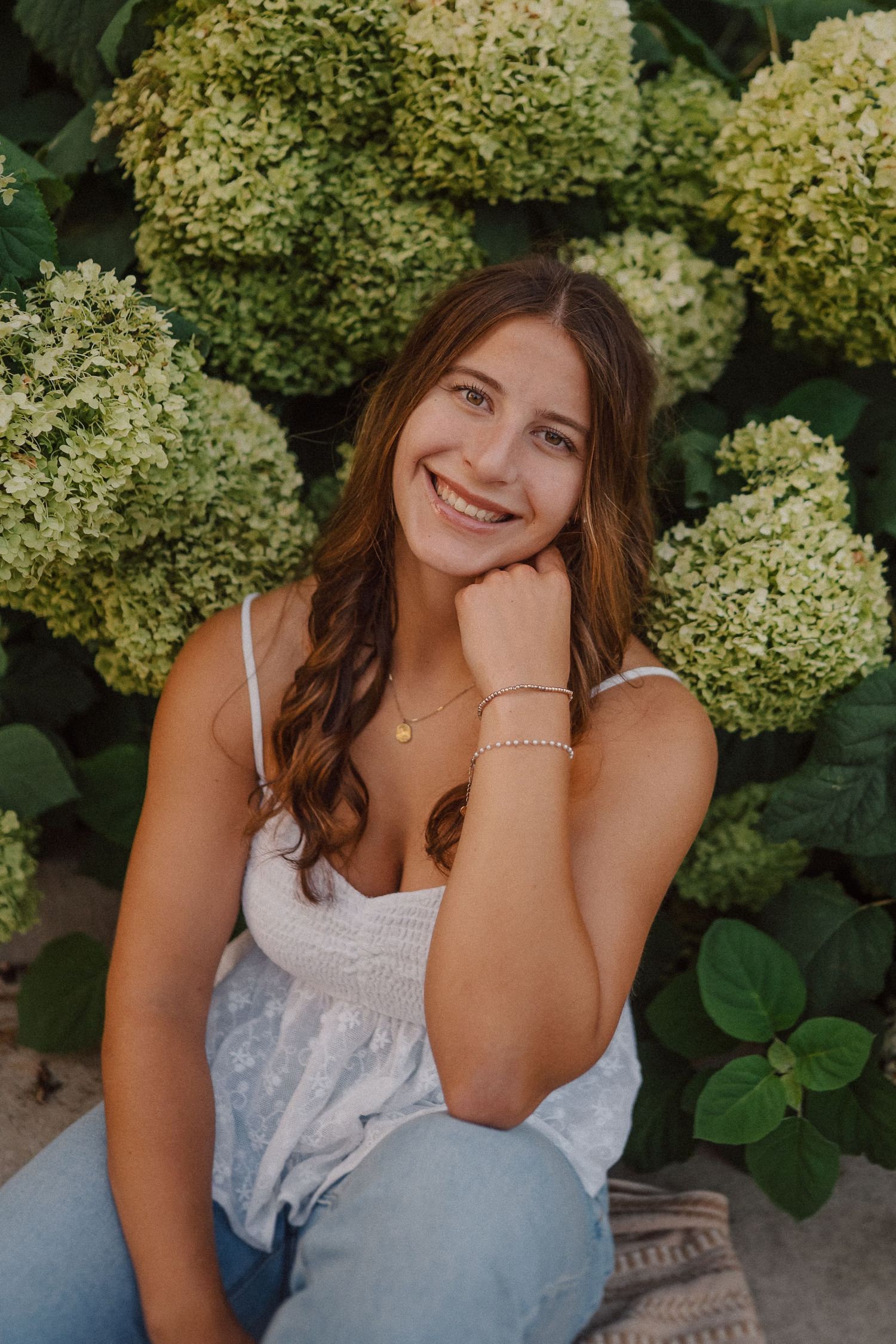 A casual summer portrait surrounded by lush green hydrangea bushes in bloom.