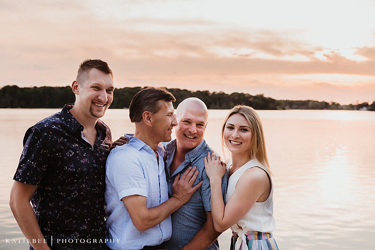 Four people sharing laughter together during a lakeside sunset photoshoot.