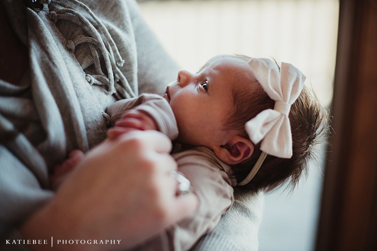 Close up of baby wearing white bow during indoor lifestyle portrait session.