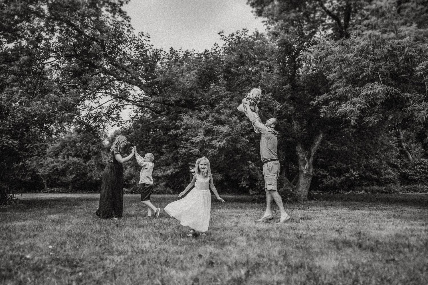Black and white photo of family playing outdoors in a natural setting.