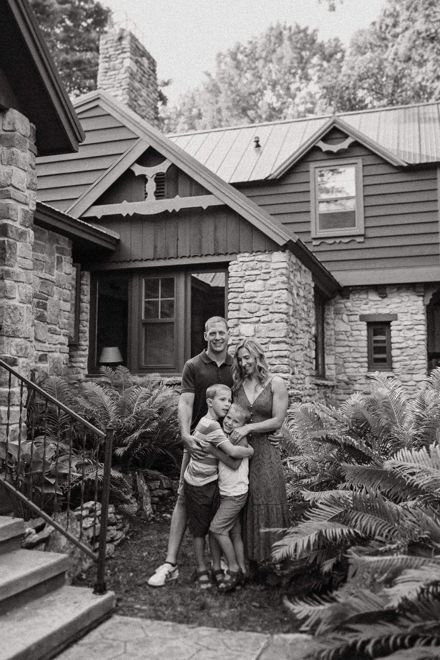 Black and white photo of a small group on stone steps of a rustic home.
