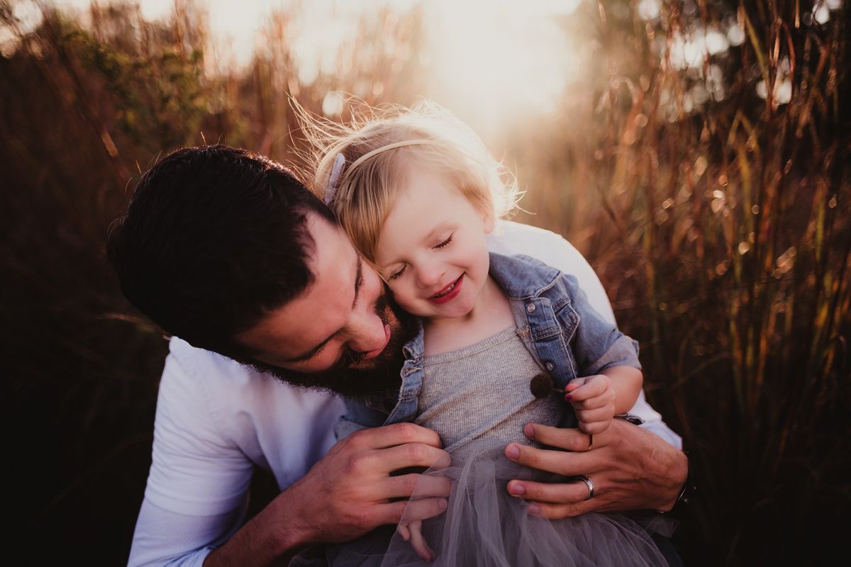Joyful moment between parent and child captured in golden sunset light.