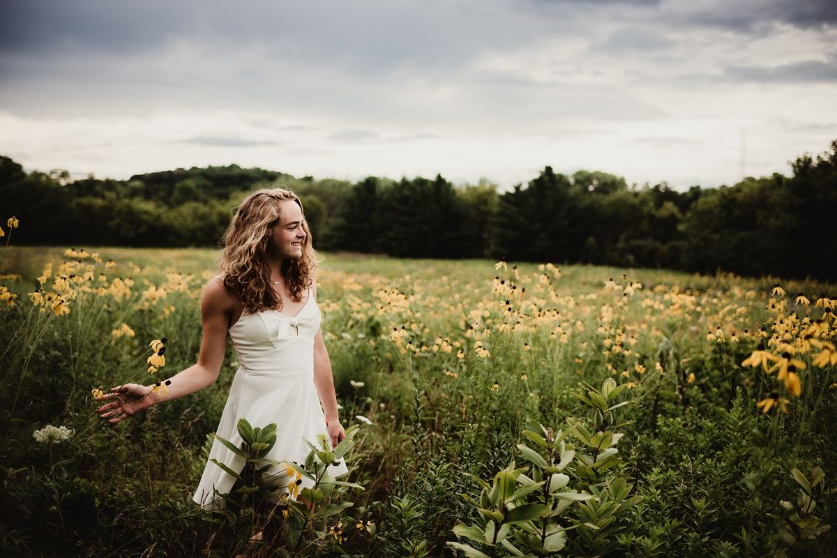 Carefree movement captured in white dress among yellow wildflowers at dusk.