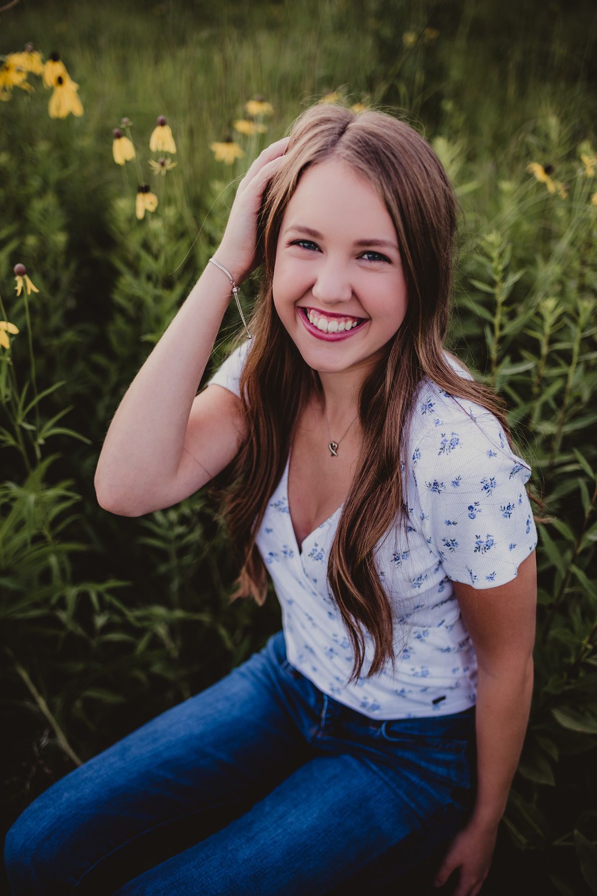 A summer outdoor portrait in a field of yellow flowers with a casual blue and white floral outfit.