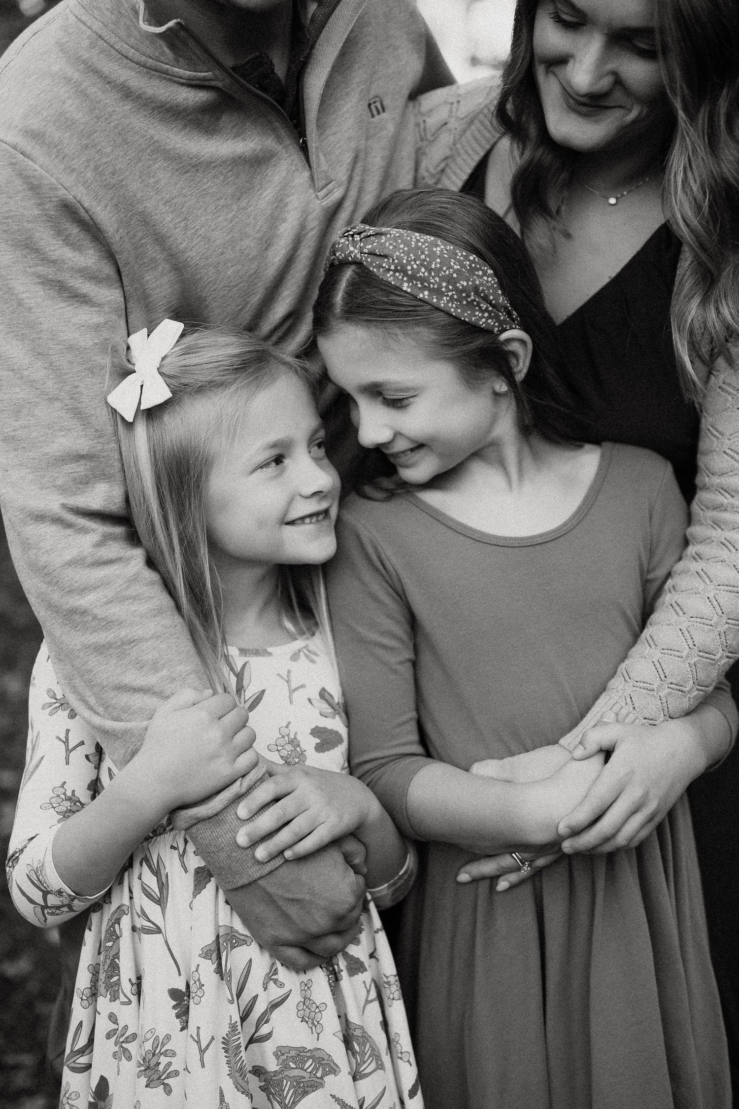 A series of black and white photos showing tender family moments with a young child in a floral dress.