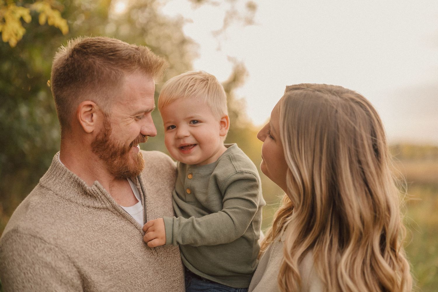 Family enjoying a tender moment together in a sunlit field during golden hour.