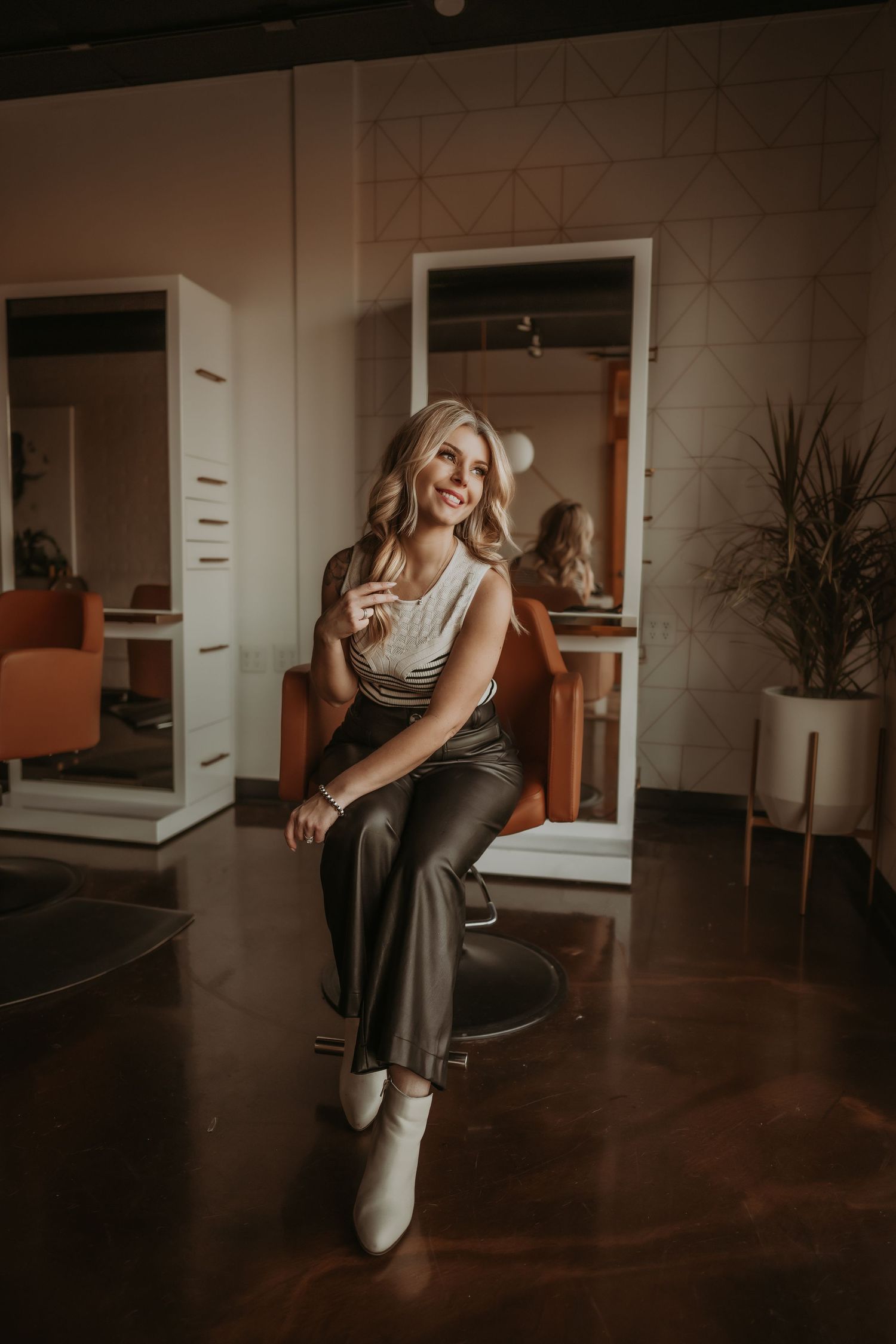 Candid salon portrait featuring elegant pose in styling chair with industrial interior elements.