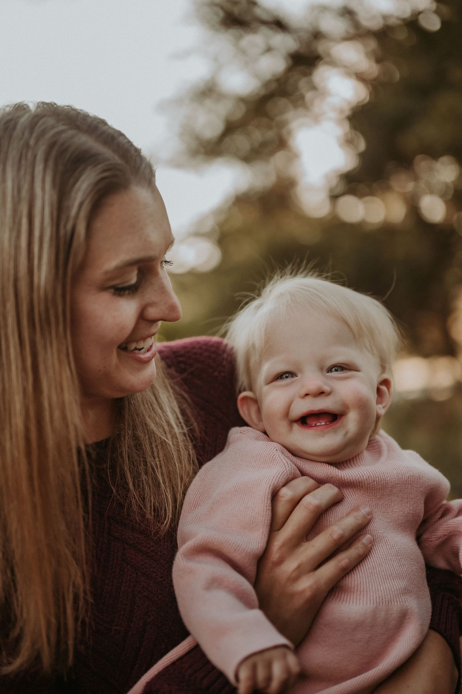 Tender moment between parent and baby captured in warm sunset lighting.