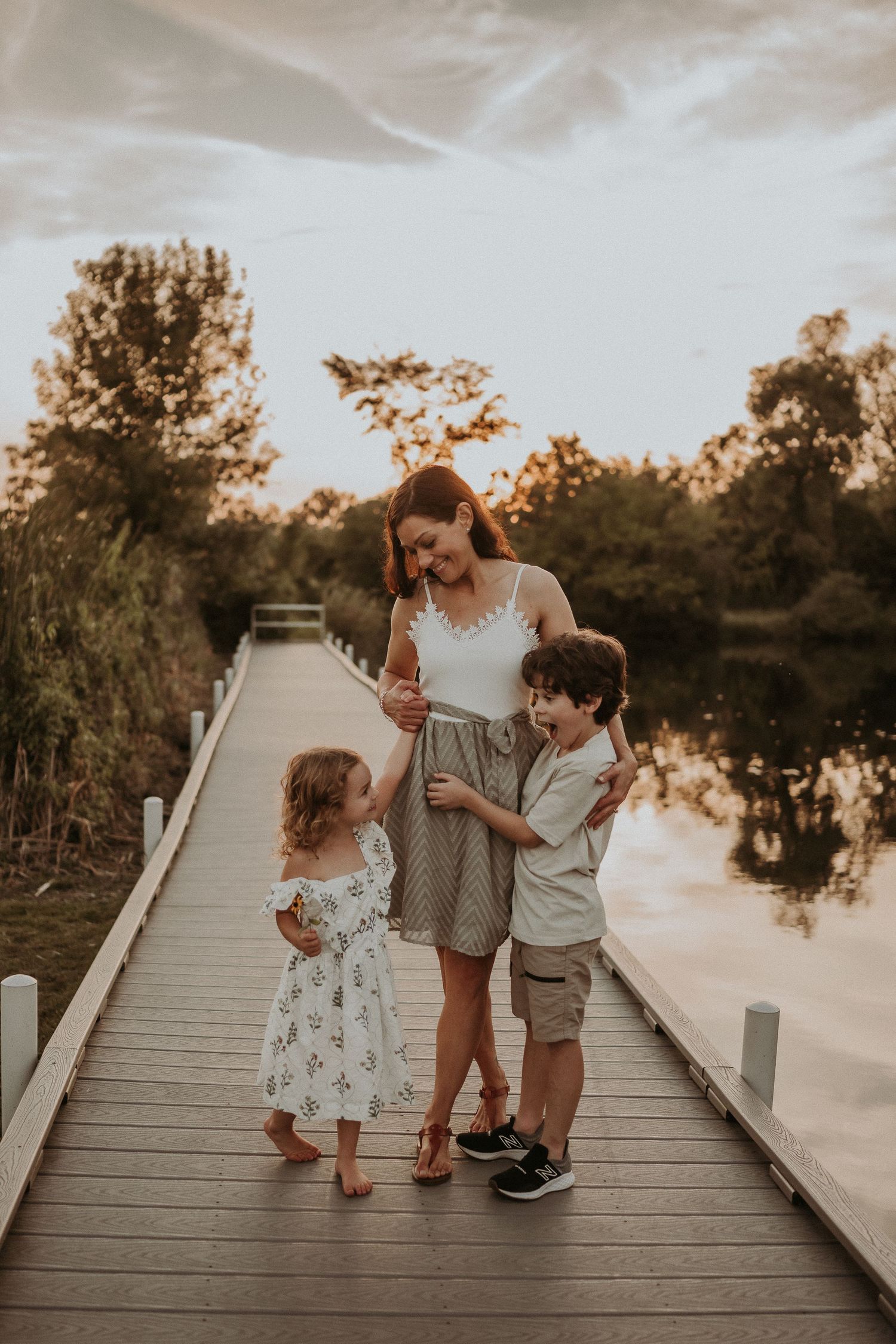 A heartwarming family moment captured on a wooden boardwalk at sunset.