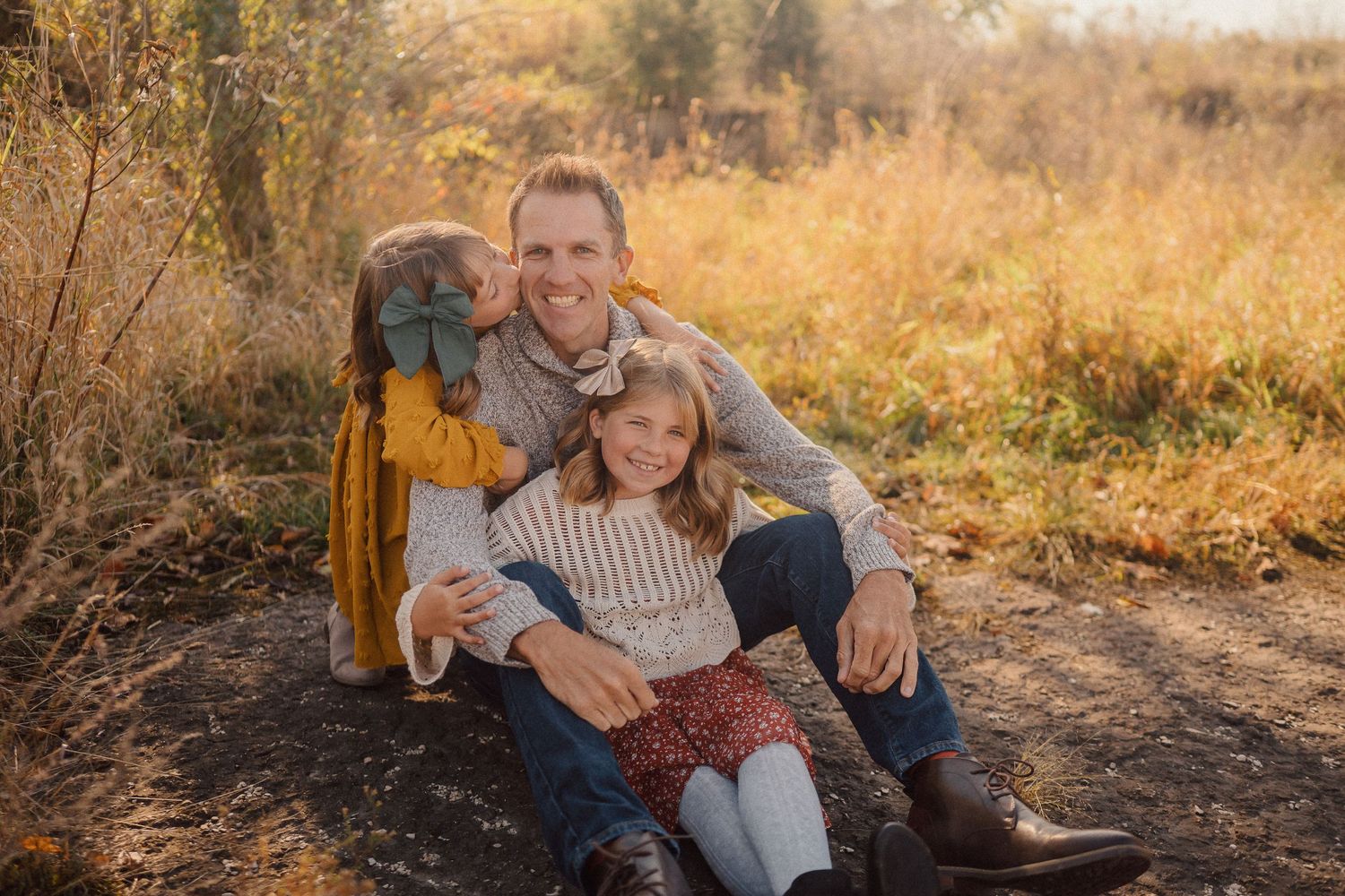 Candid family portrait session in a rustic outdoor setting during golden hour with fall colors.