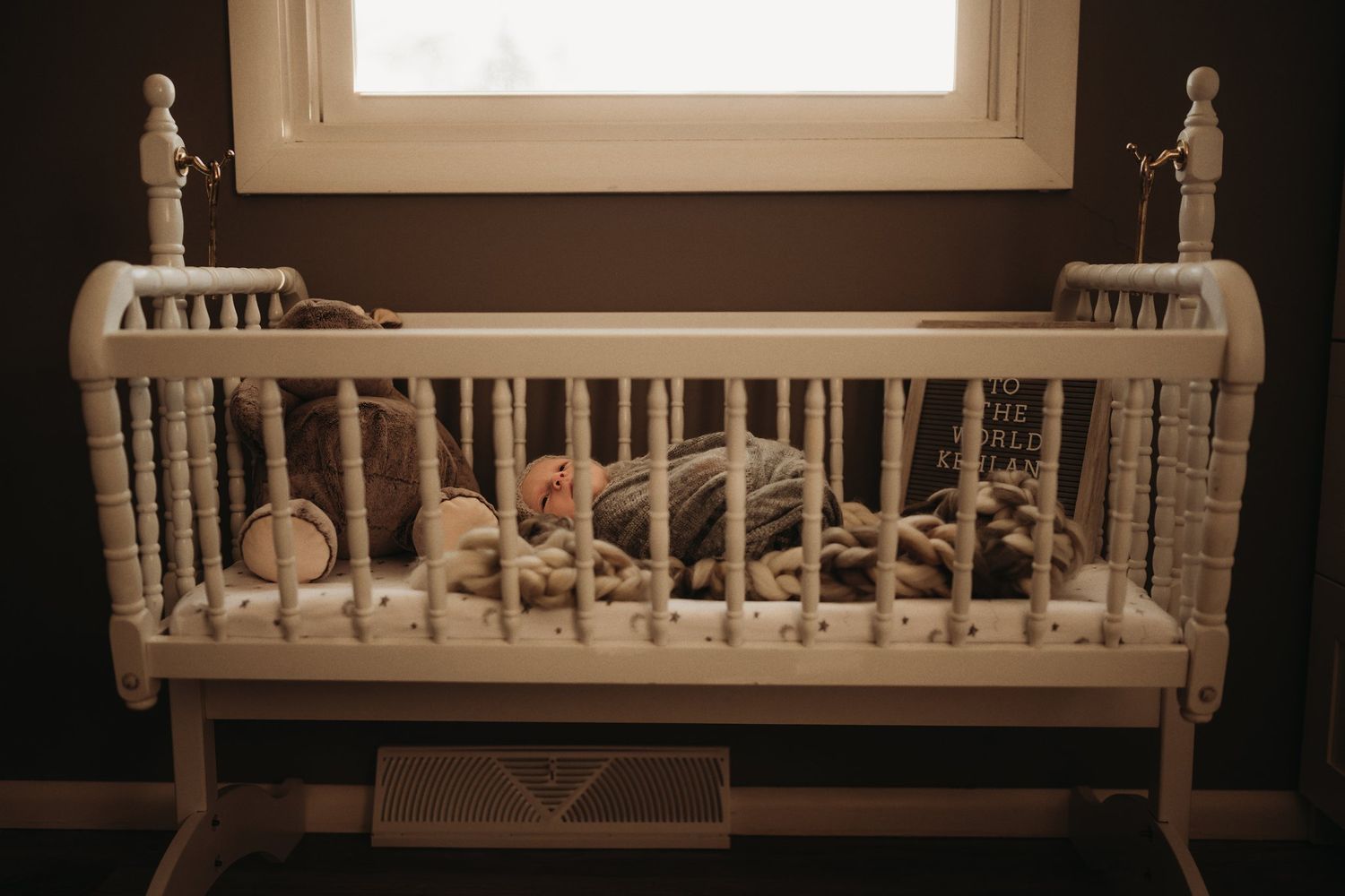Vintage white wooden crib next to window with soft natural light filtering through.
