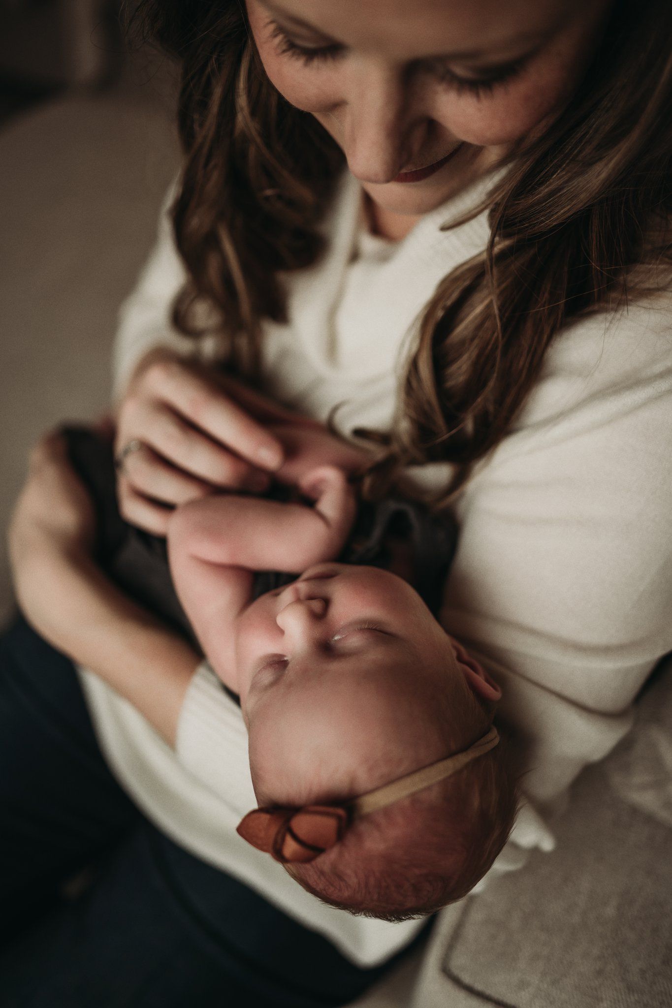 Tender close-up moment between parent and infant in warm neutral tones.