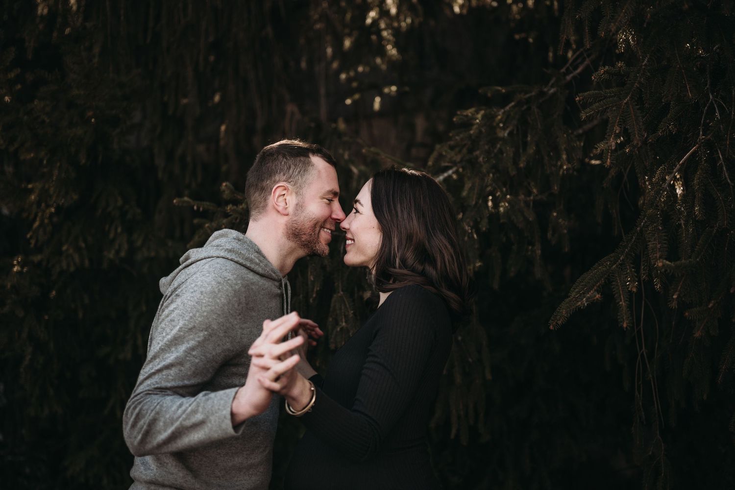 Romantic couple sharing intimate moment against dark forest background.