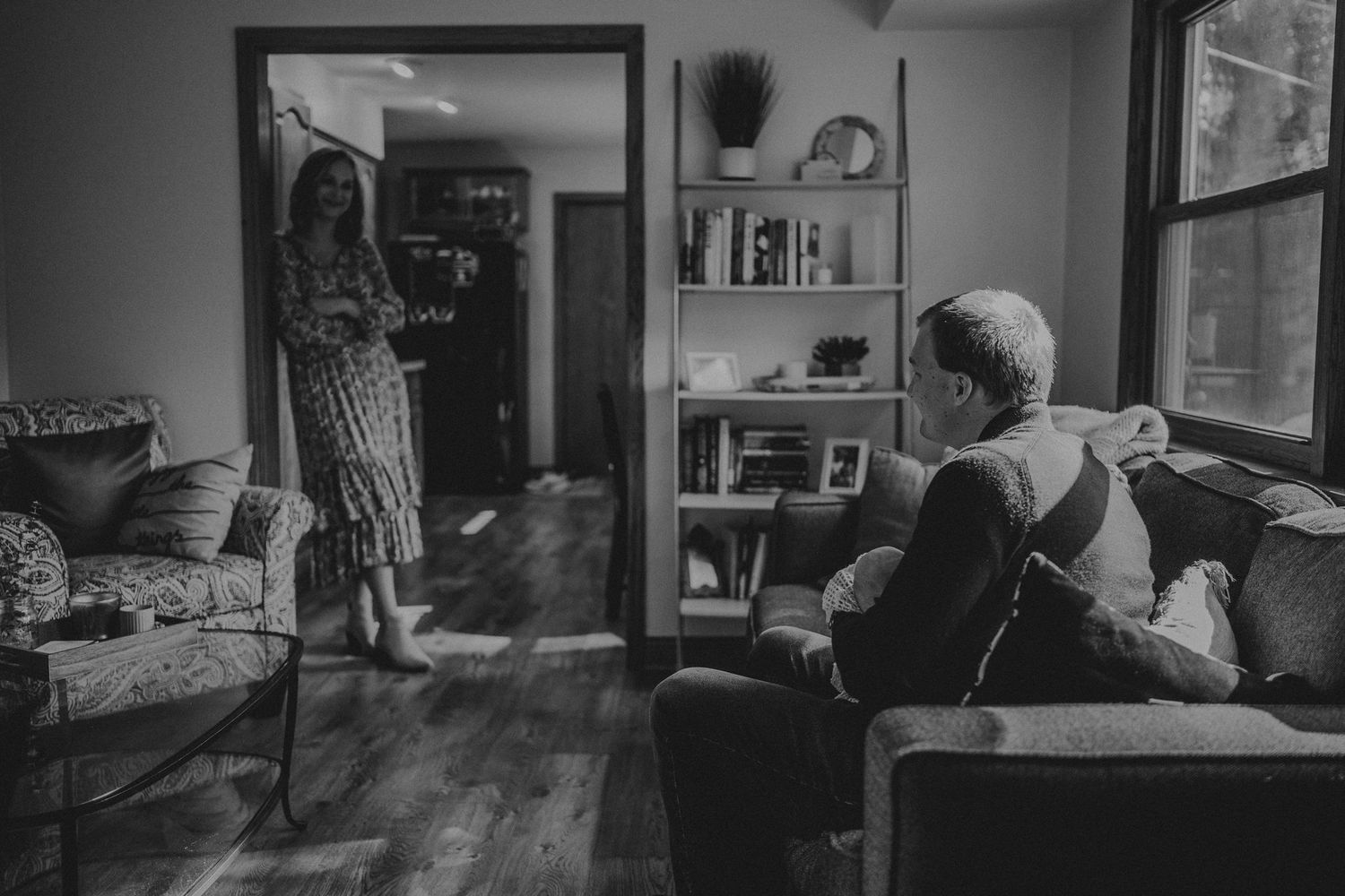 Black and white photo of a family gathering in a living room with vintage furniture.