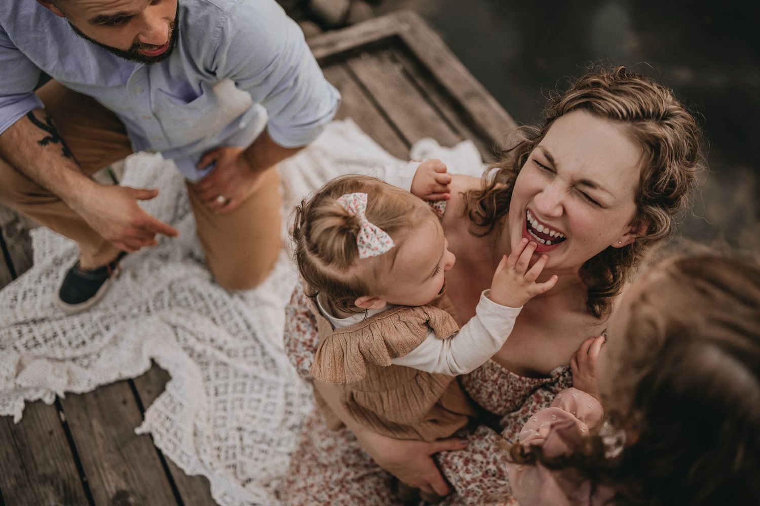 A playful family moment captured from above on a wooden deck.