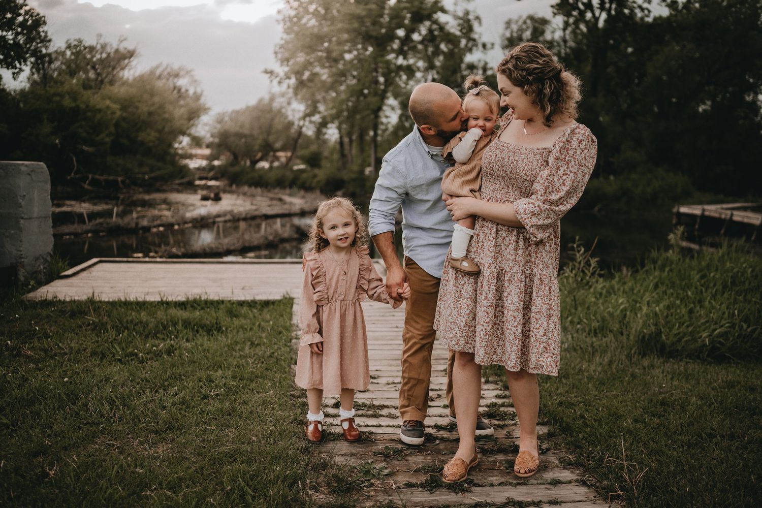 A family portrait taken outdoors with everyone wearing coordinated neutral tones.