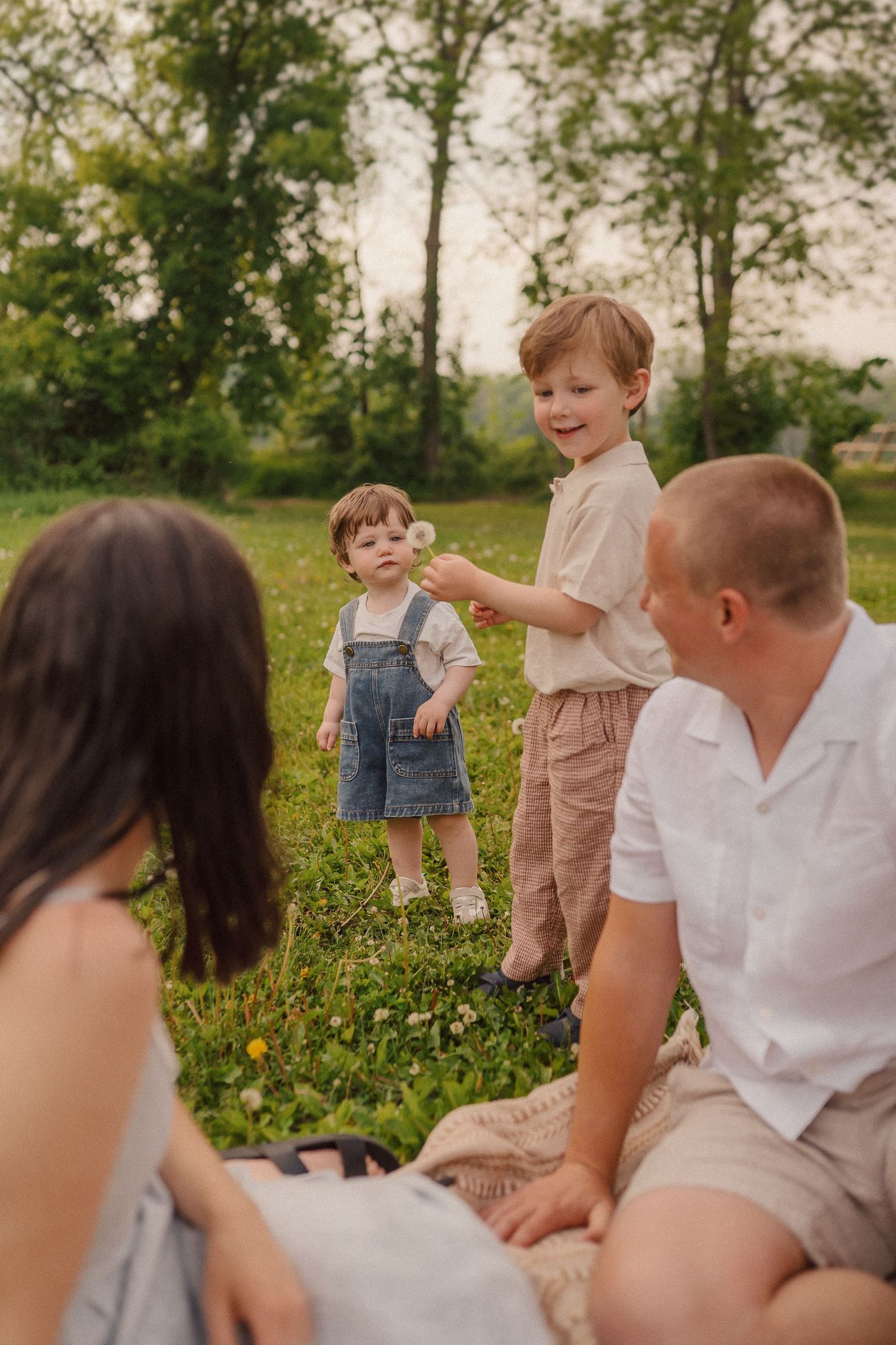 A series of candid outdoor family photos taken in a wildflower field at sunset showing playful interactions and natural moments.