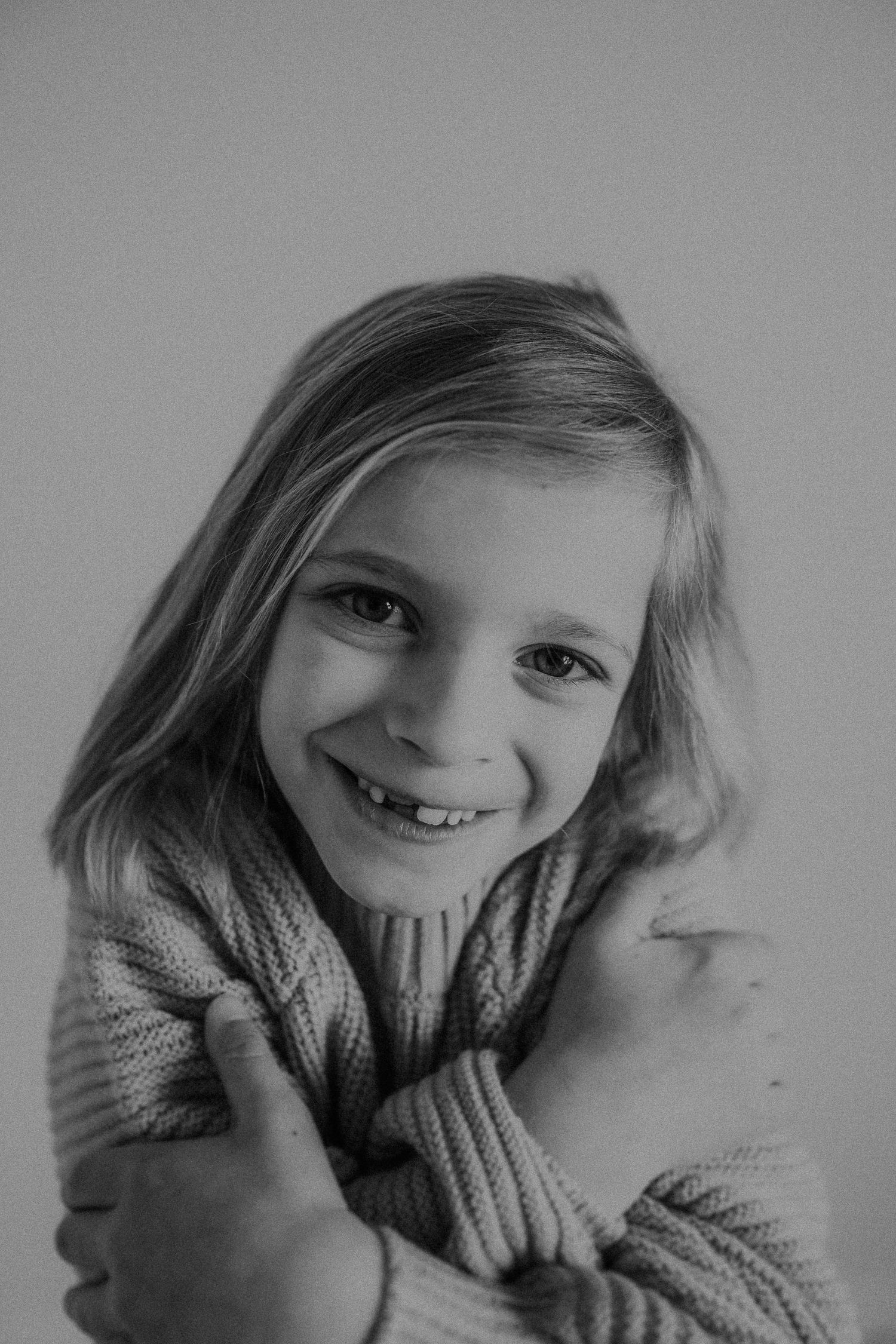 Black and white portrait capturing a genuine smile and warm knit sweater.