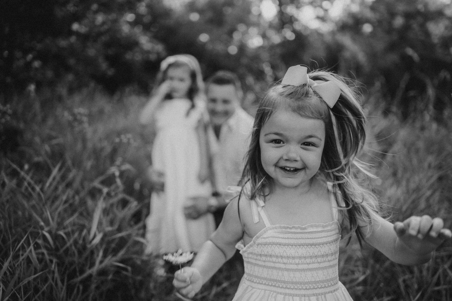 Black and white portrait of joyful expressions in a field of tall grass.