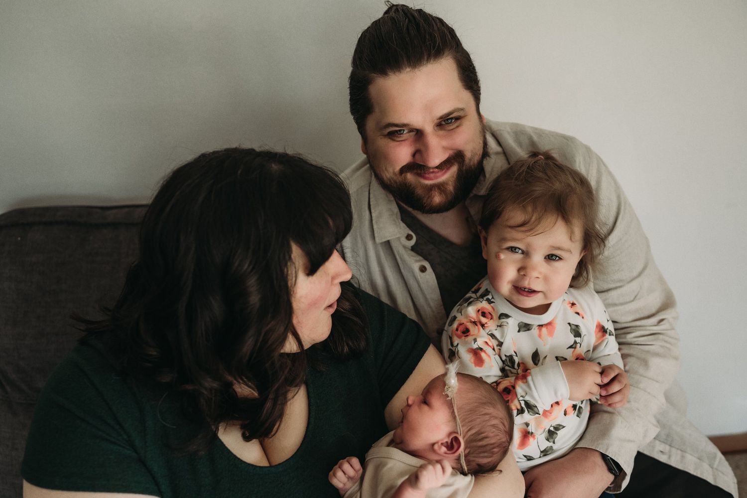 Family shares joyful moments together while relaxing on a gray couch.