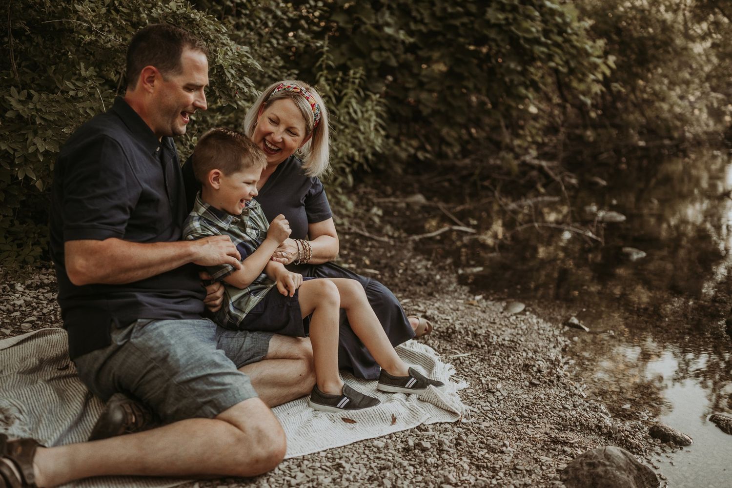 Family sharing a tender moment while relaxing by the water's edge.