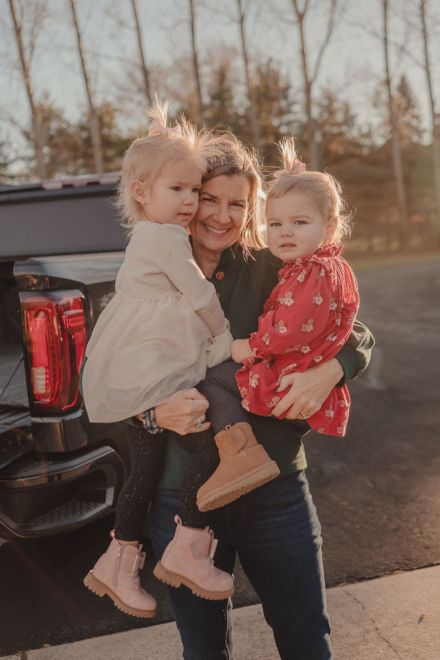 Two small children in light colored outfits are held close in an embrace by the truck.