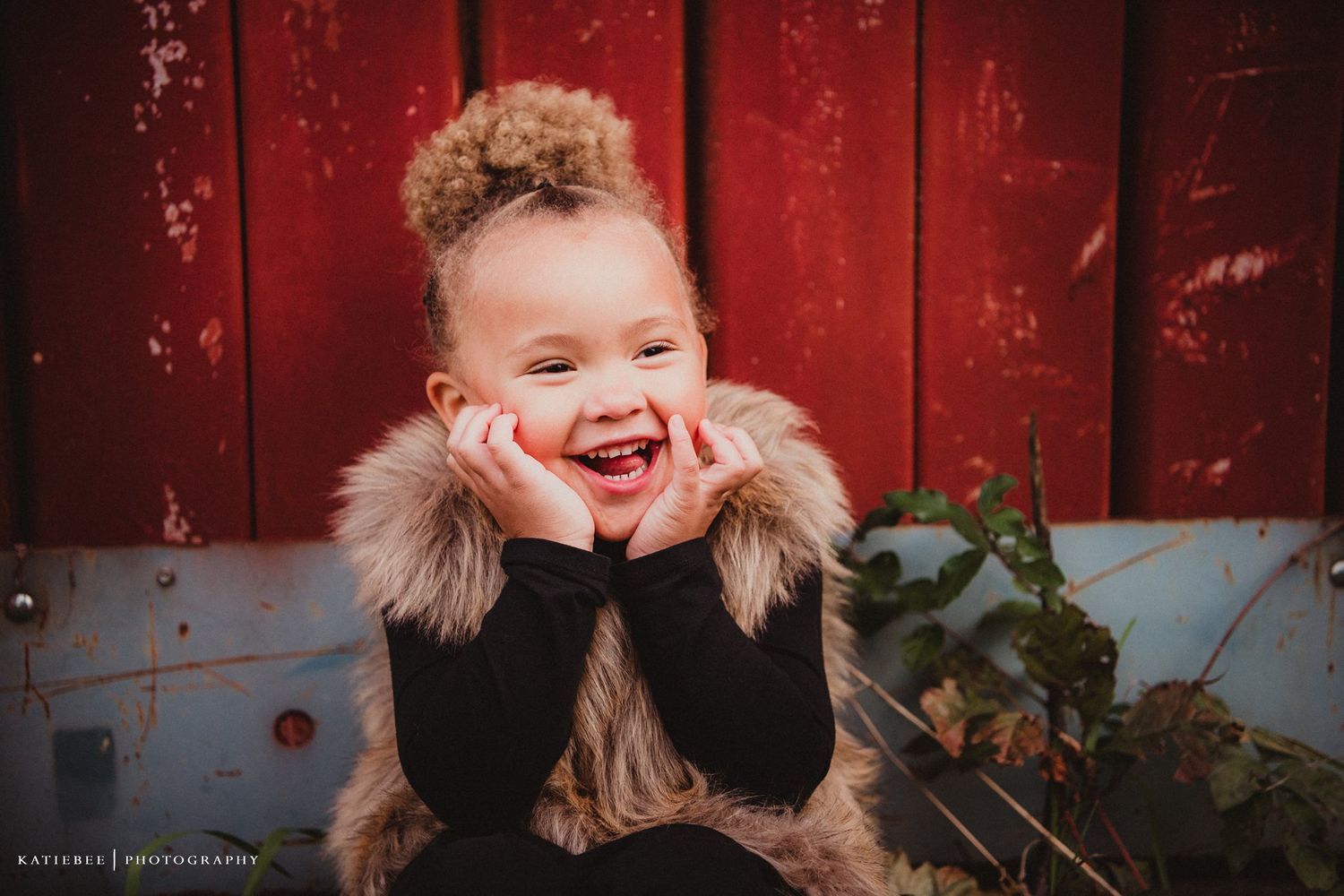 Close up portrait showing pure joy and laughter against rustic red barn background.