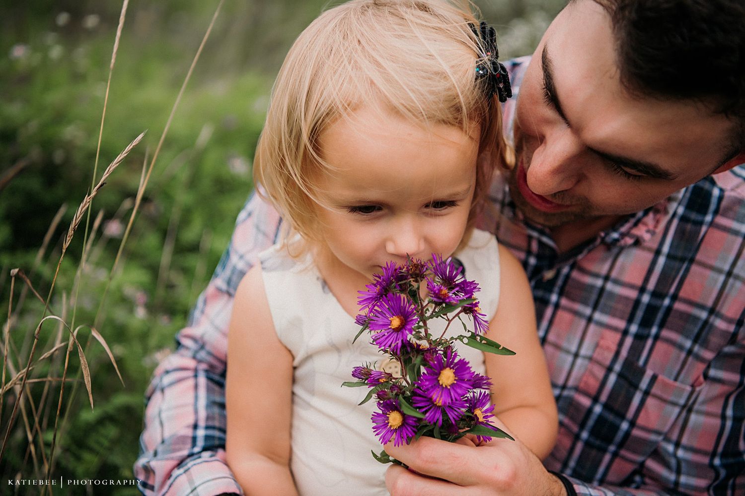 A tender moment shared with purple wildflowers in a sunlit meadow.