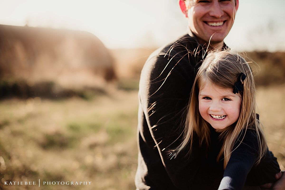 Close up portrait of happy parent and child outdoors in golden sunlight.