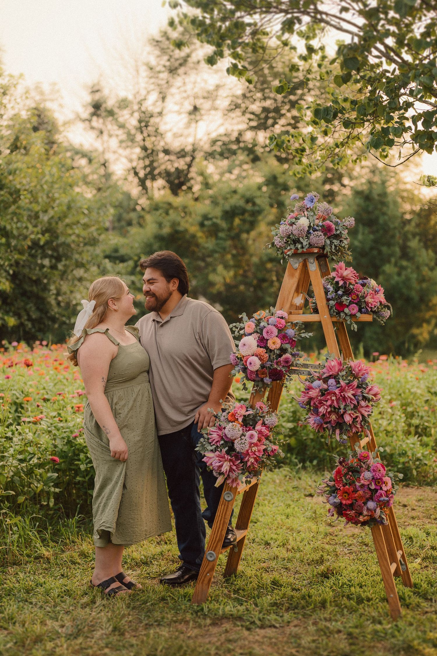 A couple sharing romantic moments in a garden setting with a floral-decorated wooden ladder in the background.