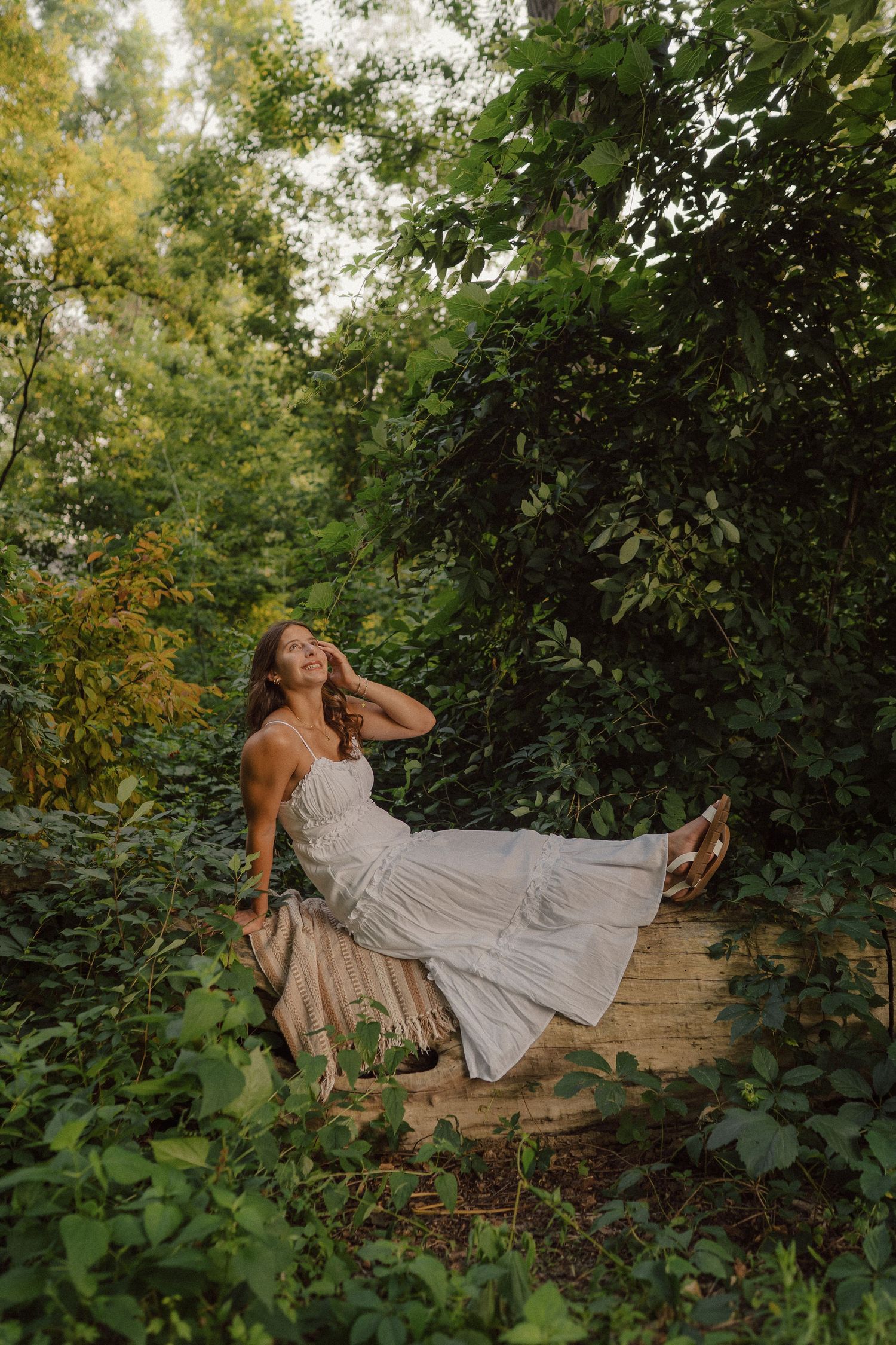A flowing white sundress contrasts beautifully against lush green foliage in an artistic outdoor photo sequence.