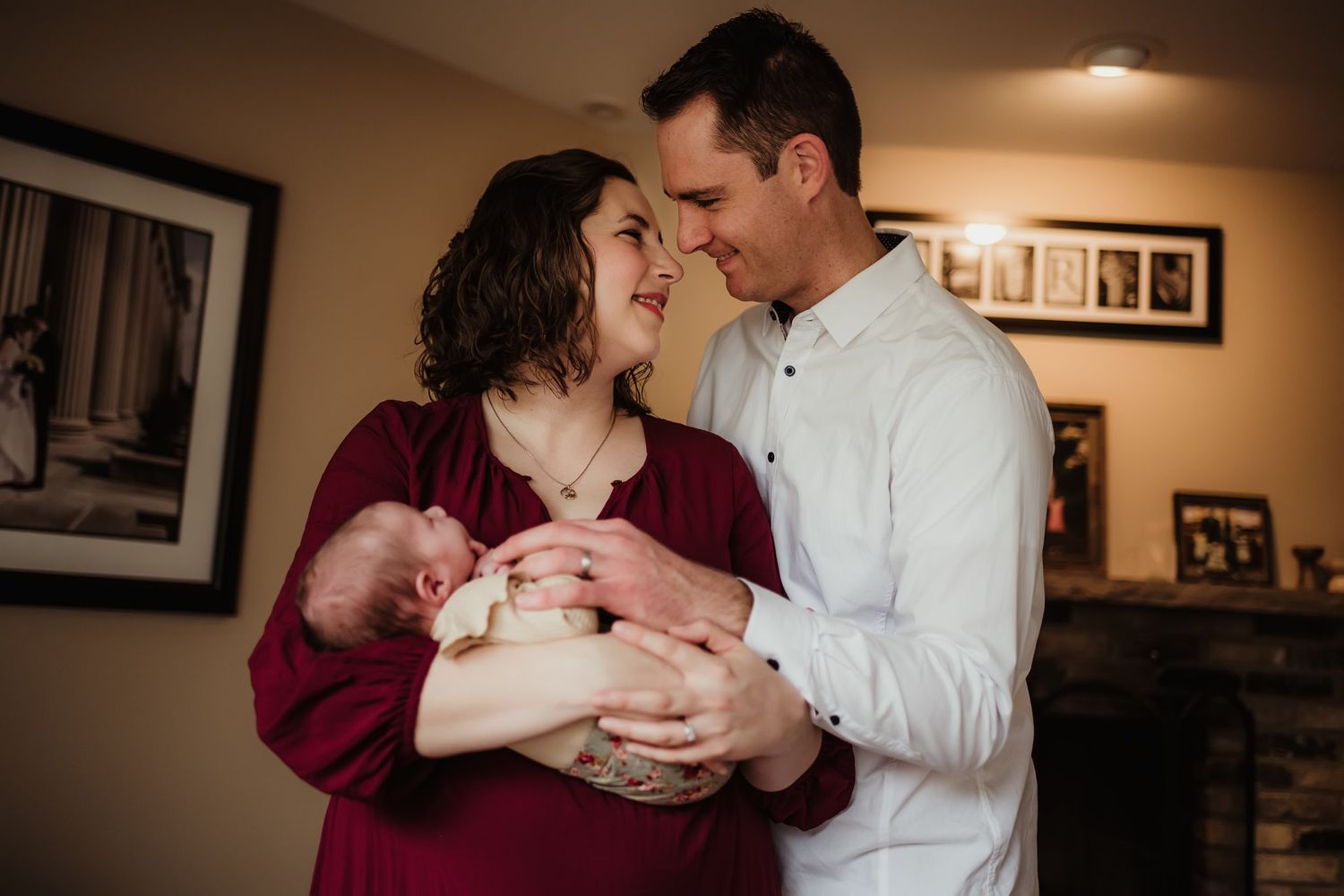 A couple shares an intimate moment with their newborn baby in a cozy home setting.