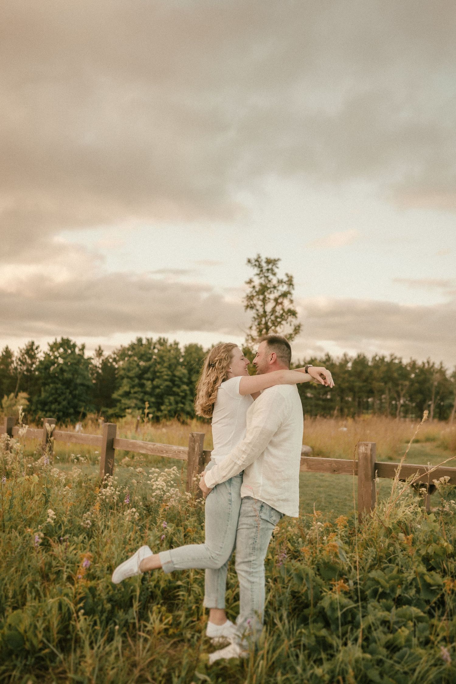 A romantic sunset portrait of a couple embracing in a wildflower meadow.